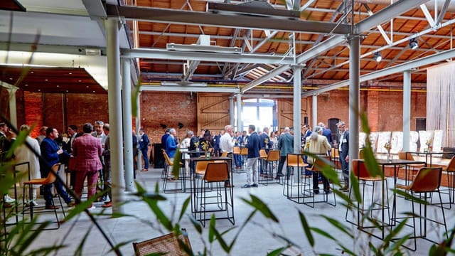 Industrial-chic lobby with brick walls and cocktail tables for networking events and receptions.