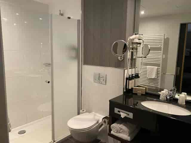 Modern hotel bathroom with glass shower in Van der Valk Brussels Airport for business conferences.