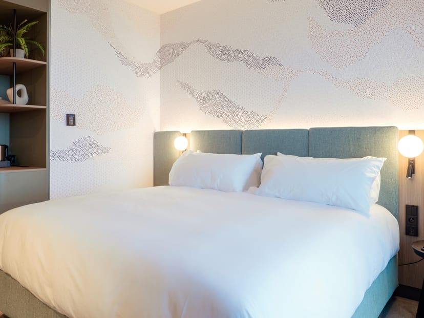 Modern guest room in voco Brussels City North with bedside lighting for business meetings and travel.