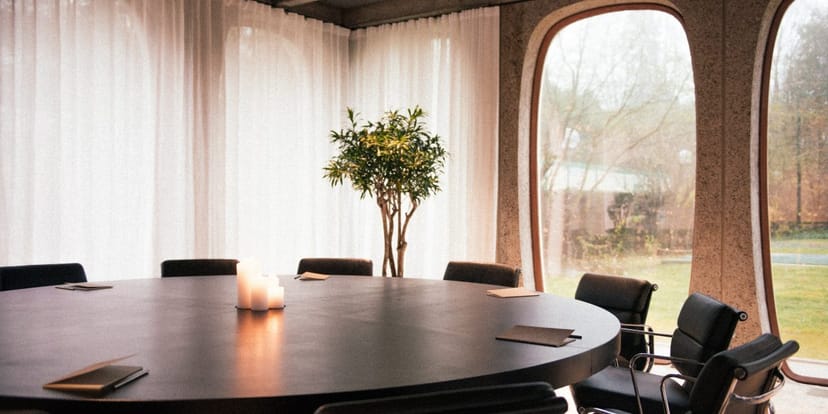 Minimalist boardroom with natural light for executive offsites and strategy meetings.