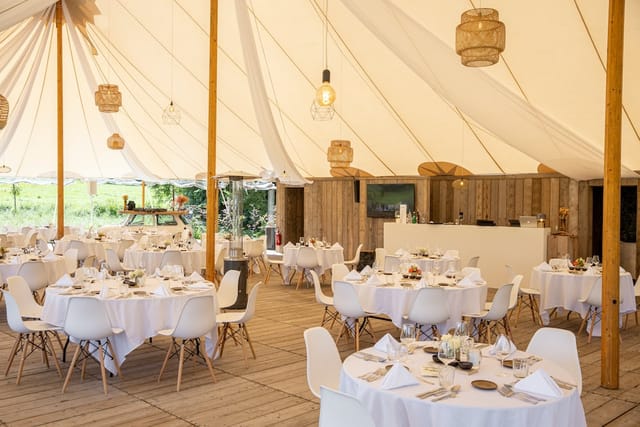 Rustic marquee event hall in Kattebroek with modern seating and ambient lighting.