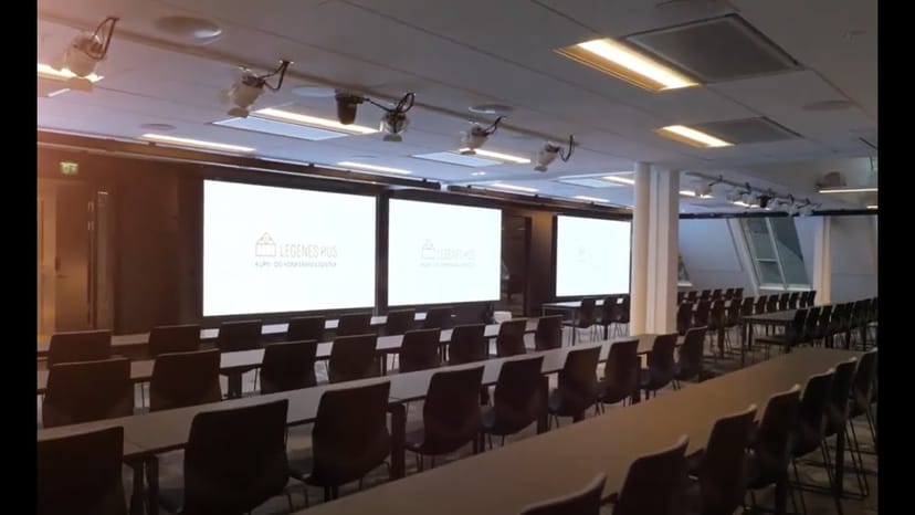 Classroom-style conference room with triple screens for corporate events and business seminars.
