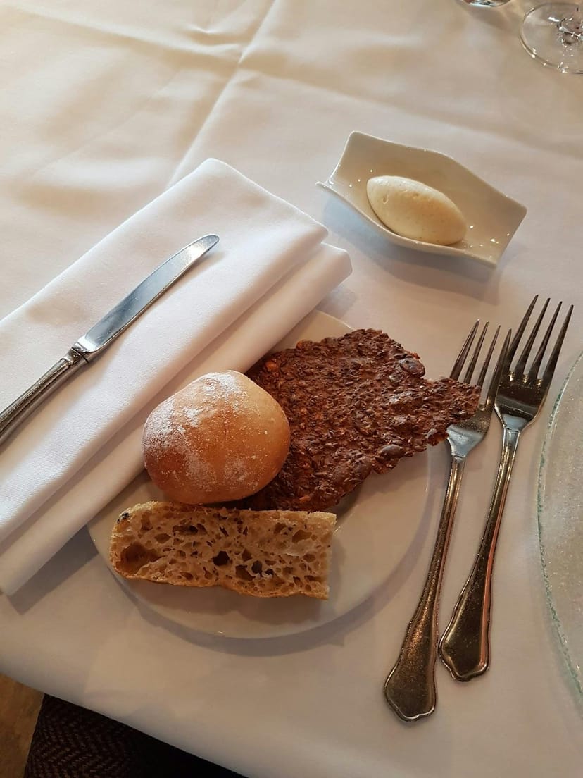 High-end restaurant bread service with misaligned flatware for catering event setup.