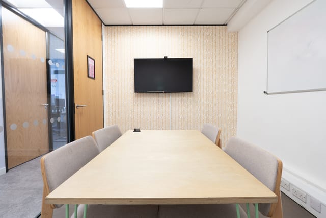 Mary in modern meeting room with wall-mounted TV for collaborative gatherings.