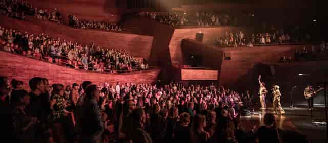 Multi-level concert hall with atmospheric lighting for keynote session or corporate event venue.