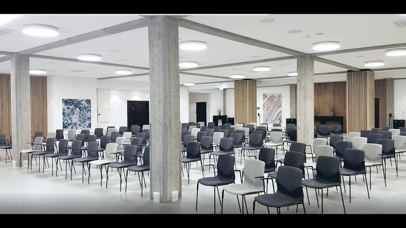 Modern theater-style atrium conference room with structural pillars for corporate events.