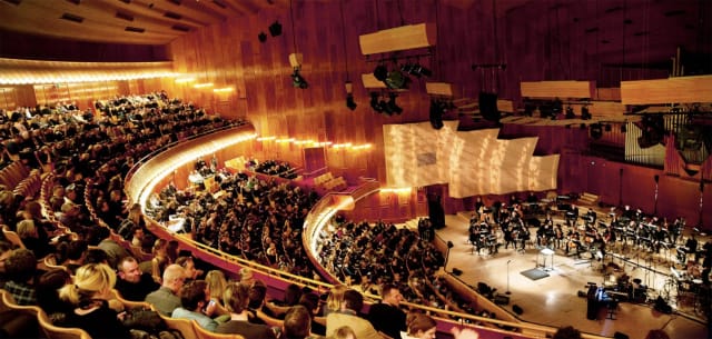 Tiered auditorium at The Concert Hall with stage rigging for plenary sessions and keynotes.