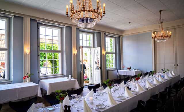 Elegant banquet hall with chandeliers set for a formal long-table dinner event.