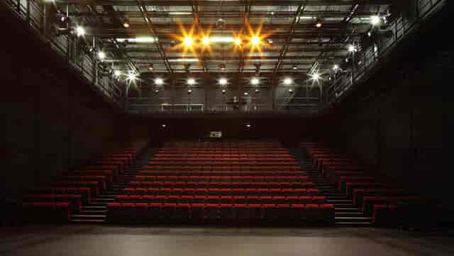 Industrial black-box theater with tiered seating for corporate keynotes and product launches.