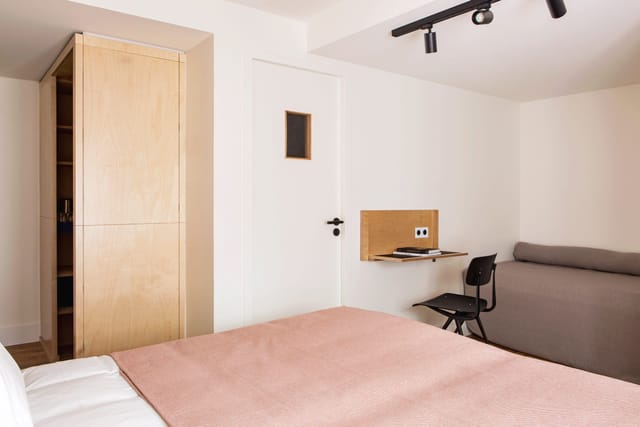 Minimalist micro-hotel room with workspace for business travel and urban event accommodation.