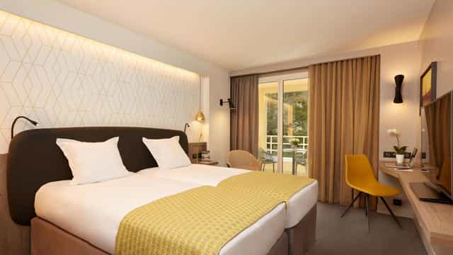 Twin-bedded hotel suite with workspace and balcony for business travel and corporate conferences.