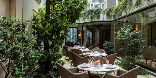 Private garden brunch setting with wicker seating for intimate event networking.