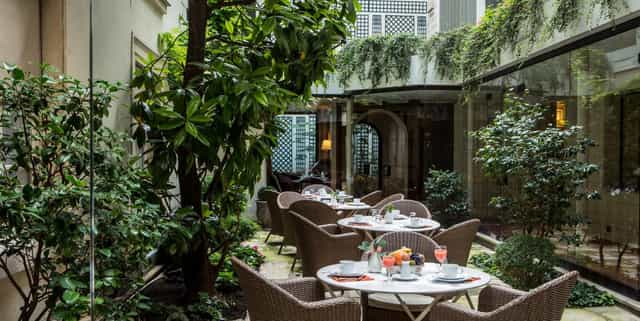 Private garden brunch setting with wicker seating for intimate event networking.