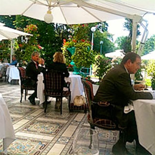 Elegant outdoor corporate luncheon setup at La Grande Cascade with umbrella-shaded dining tables.