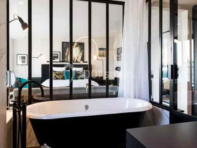 Modern hotel suite with industrial glass bathroom partition for corporate travel.