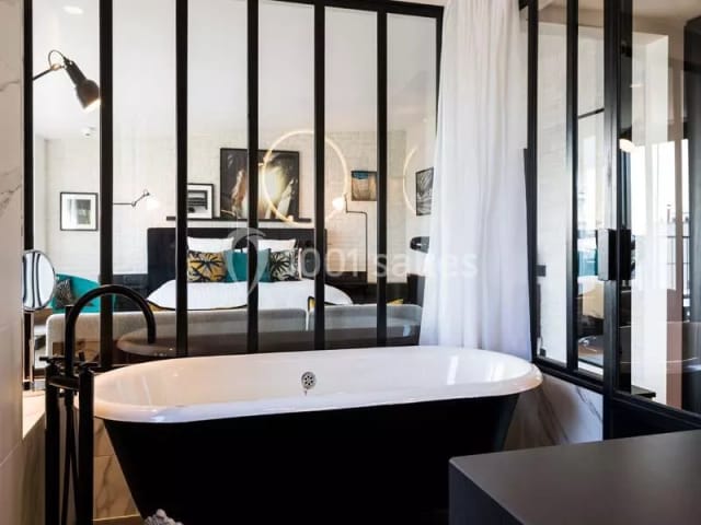 Modern hotel suite with industrial glass bathroom partition for corporate travel.