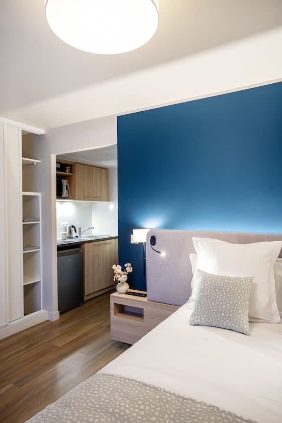 Modern studio hotel room with kitchenette for business travel and extended stay accommodation.