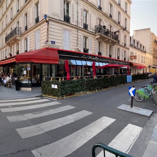 Charming outdoor restaurant in Le Marly with vibrant red awning, ideal for networking events.