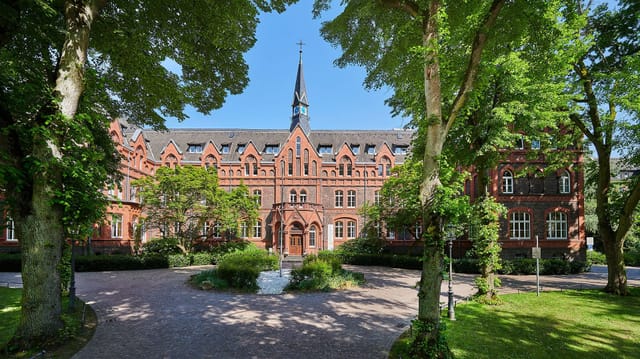 Historic brick Great Hall at Hotel MutterHaus Düsseldorf, ideal for upscale retreats and conferences.
