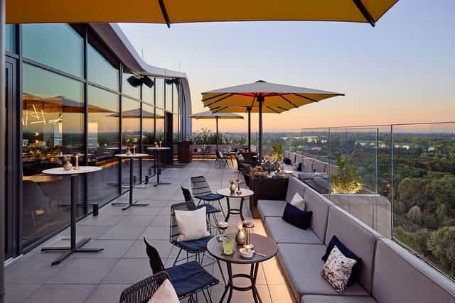 Corporate cocktail reception on The Roof Dusseldorf terrace at sunset for networking events.