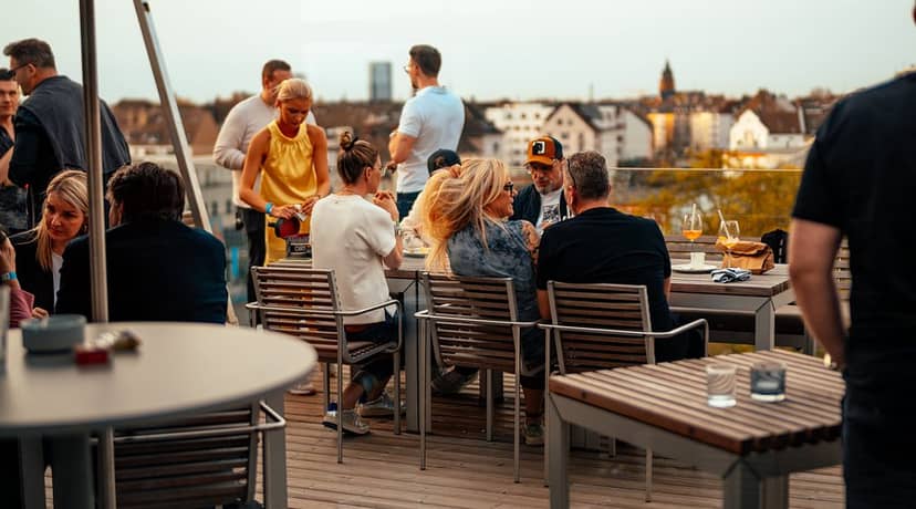 Rooftop networking reception at The Roof Dusseldorf with sunset skyline, ideal for corporate events.