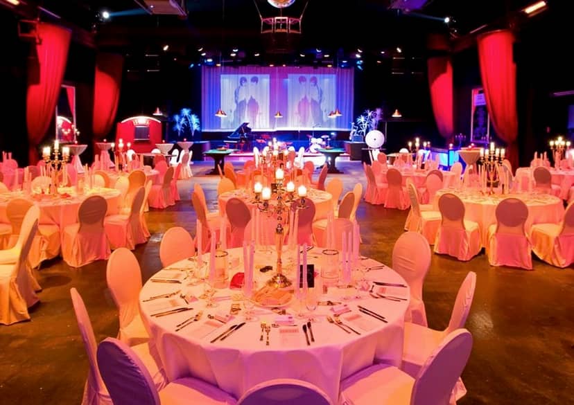 Theater der Träume gala foyer with red lighting, stage setup, and formal banquet seating.