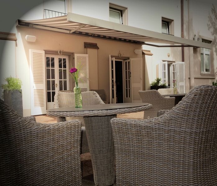 Shaded wicker seating at Hotel Hanseat terrace, ideal for intimate breakout sessions and networking.