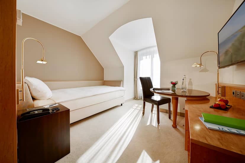 Single-occupancy hotel room with dedicated workspace for conference business travel.