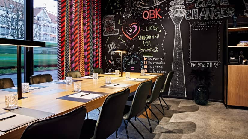Modern Hotel Duesseldorf boardroom with interactive chalkboard wall for creative workshops.