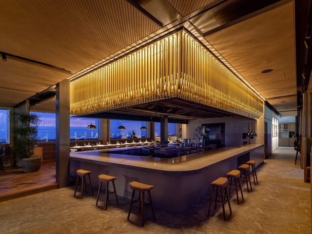Upscale rooftop venue with illuminated bar for corporate cocktail reception and networking event.