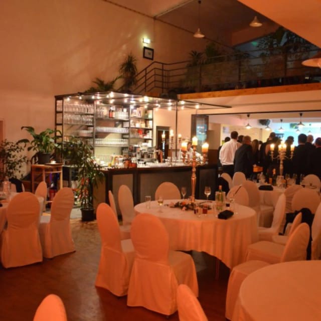 Industrial-chic event hall at Schlossallee 1 with ambient lighting for evening reception and gala.