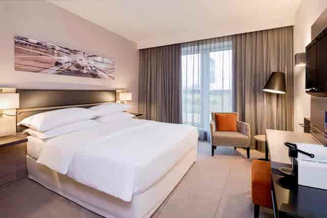 Modern Sheraton Düsseldorf Airport hotel room with desk for business meetings and corporate events.