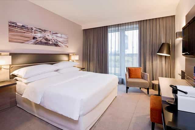 Modern Sheraton Düsseldorf Airport hotel room with desk for business meetings and corporate events.