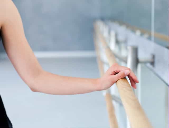 Dancer's hand on ballet barre at Unfurl Studios, showcasing elegance for events and performances.