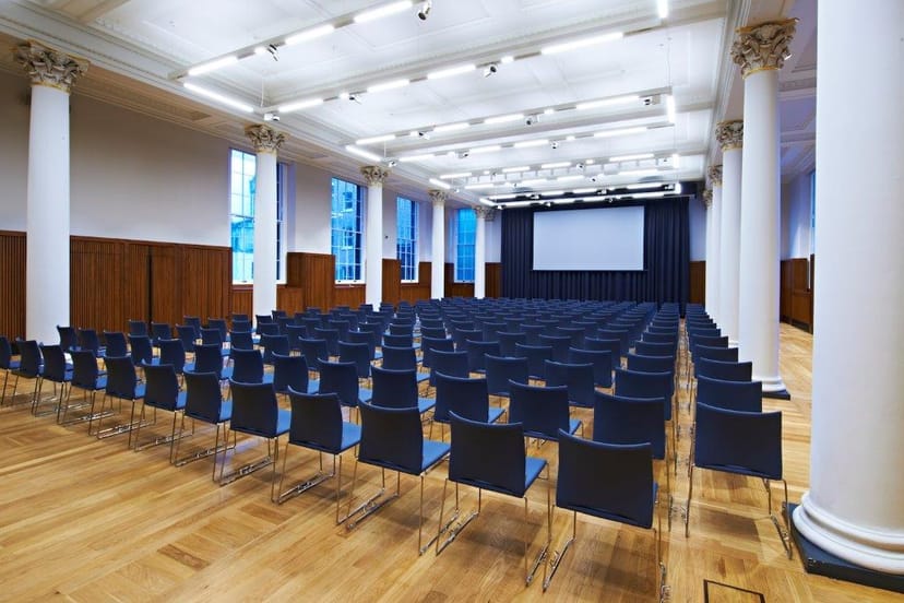 Great Hall at King's College London set for conferences, featuring modern chairs and high ceilings.