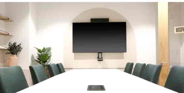 Modern meeting room in Runway East Birmingham with sleek table and green chairs.