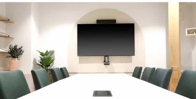Modern meeting room in Runway East Birmingham with sleek table and green chairs.