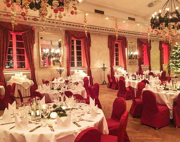 Wolkenburg ballroom with red chair covers for a corporate holiday gala and winter event.