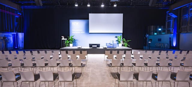 Professional fireside chat stage setup in a modern minimalist corporate event hall.