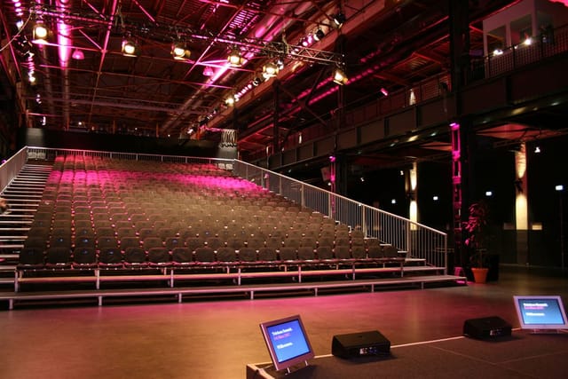 Industrial Palladium Köln concert hall with tiered theater seating for corporate presentations.