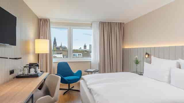 Modern hotel room with workspace and city view for business travel and conference stays.