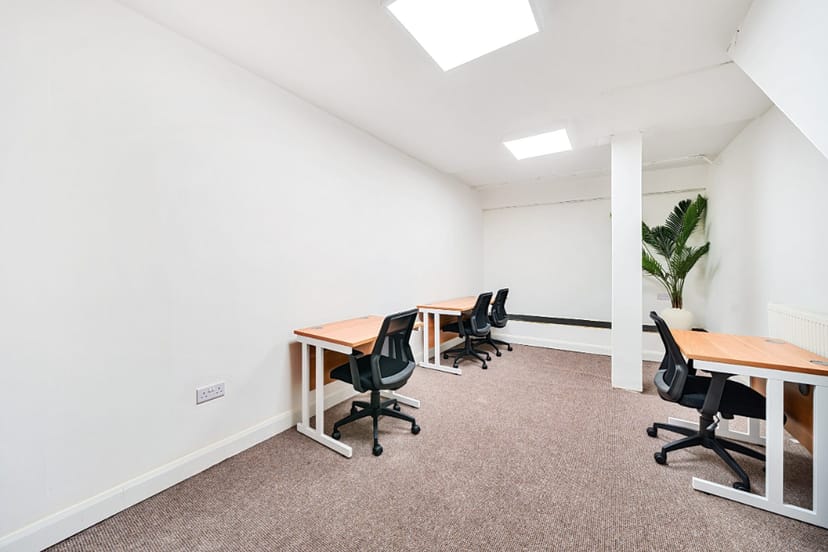 Minimalist meeting room with workstations and natural light at Hub 56, perfect for collaboration.