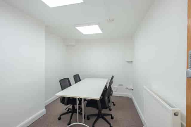 Minimalist meeting room at Hub 56, bright skylights, ideal for focused discussions.