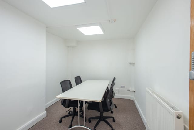 Minimalist meeting room at Hub 56, bright skylights, ideal for focused discussions.