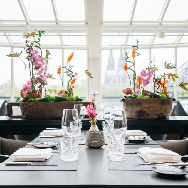 Upscale Glashaus Restaurant with floral decor and Cologne Cathedral view for corporate gala dinner.