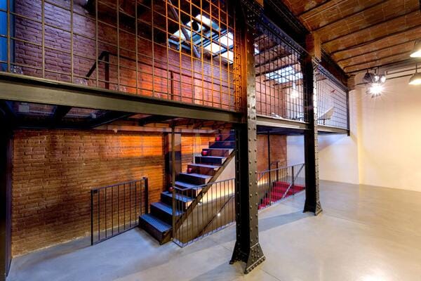 Industrial loft auditorium with multi-level breakout zones for corporate events and workshops.