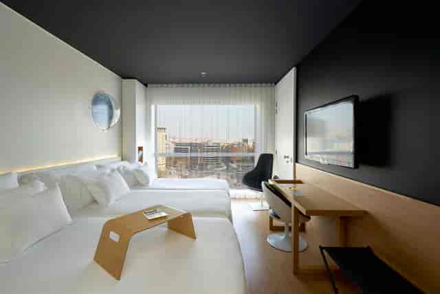 Modern twin guest room at Barceló Sants with ergonomic workspace for business travel events.