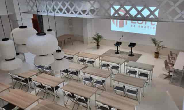 Industrial-chic corporate event venue with stage, ideal for professional conferences and workshops.