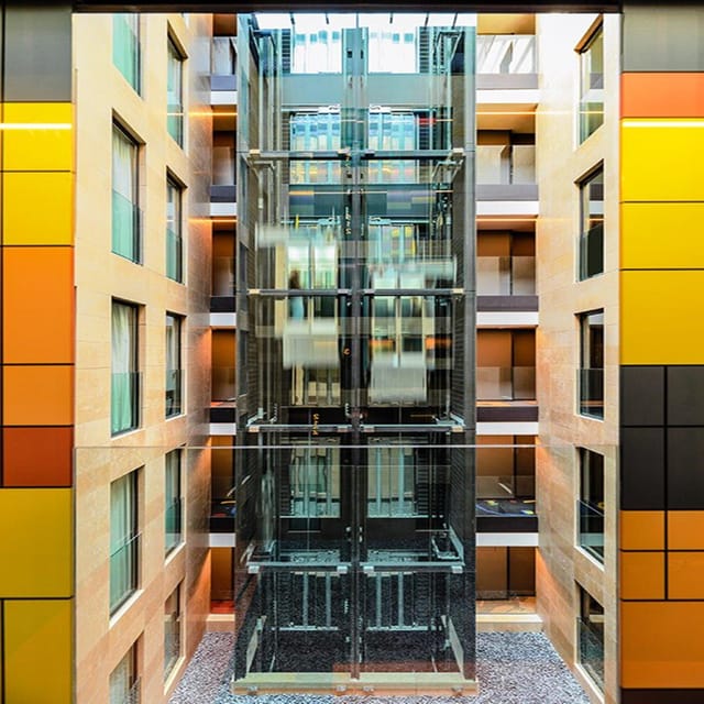 Modern hotel atrium with glass elevator bank for event venue and conference planning.