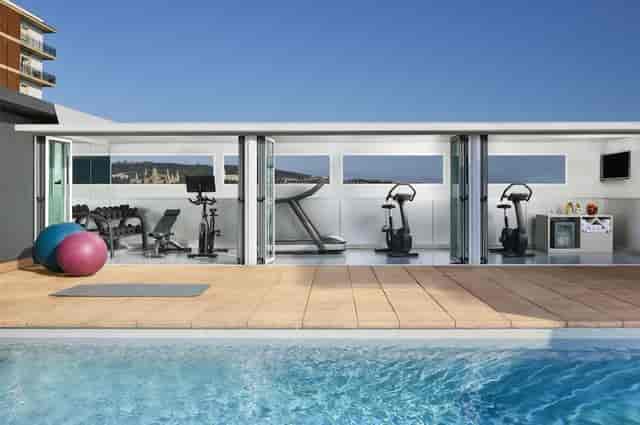 Modern fitness center with pool access at NH Barcelona Stadium for corporate wellness retreats.